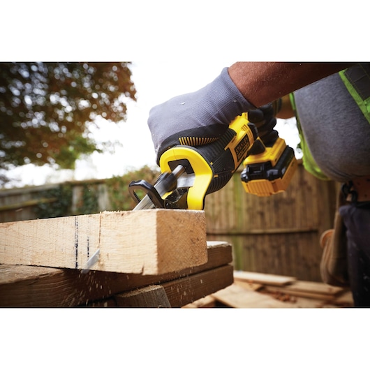 Photo of STANLEY FMC675B cordless reciprocating saw cutting wood, close-up showing tool in use outdoors.