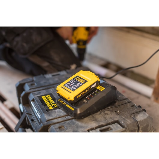 STANLEY FMC687L yellow 18V lithium battery charger on toolbox, workshop setting.