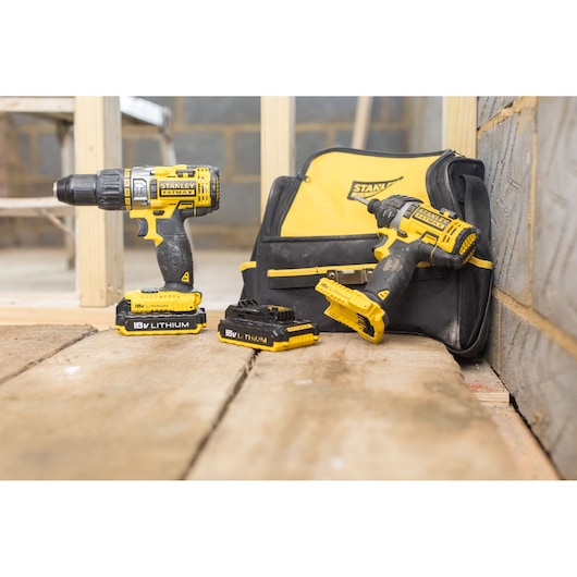 STANLEY FMCK461C2 cordless drill and impact driver set with 18V lithium batteries and tool bag on wood floor.