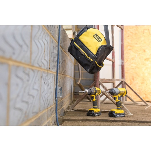 STANLEY FMCK465C2S drill and impact driver set with yellow and black tool bag on construction site floor.