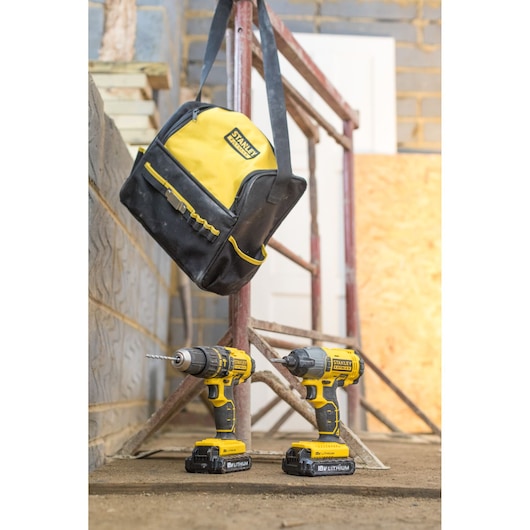 STANLEY FMCK465C2S cordless drill and impact driver kit with yellow-black tool bag, photographed on a construction site.