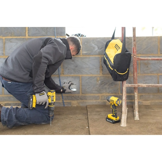 STANLEY FMCK465C2S photography showing worker using cordless drill, tool bag, and drill kit at construction site.
