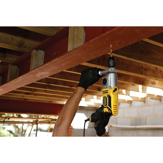 STANLEY FME142K drill in use drilling into a steel beam during construction, close-up view.