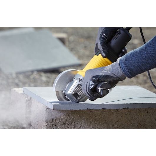 STANLEY FMEG210K angle grinder used on stone tile, close-up photo showing tool in action.