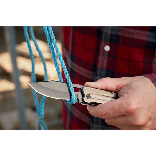 STANLEY FMHT0-10311 folding knife cutting blue rope, close-up outdoor view.