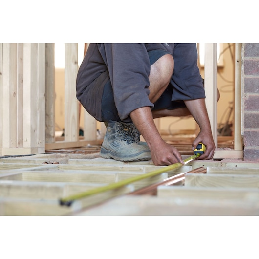 STANLEY FMHT0-36326 tape measure used for measuring wood frame in construction site.