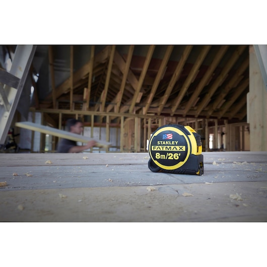 STANLEY FATMAX 8m/26' tape measure FMHT0-36326 on a construction site floor, wood framing in background.