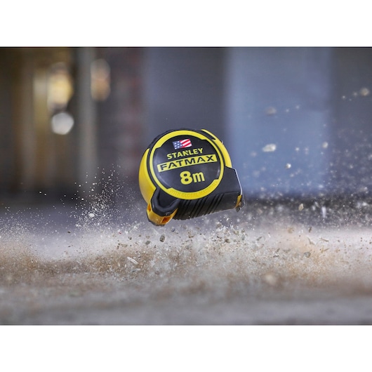 STANLEY FATMAX 8m tape measure, SKU FMHT0-36327, photography of product impacting dusty ground.