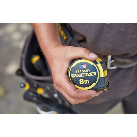 Stanley FMHT0-36327 FatMax 8m tape measure held in hand, yellow and black, close-up view.