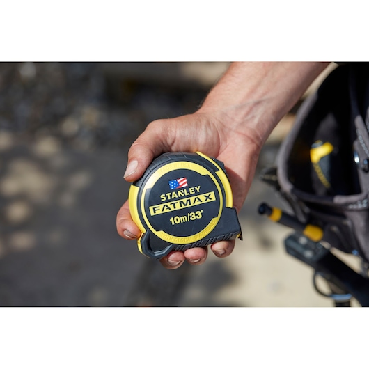 Photo of STANLEY FMHT0-36336 tape measure, yellow and black, held in hand, close-up view.