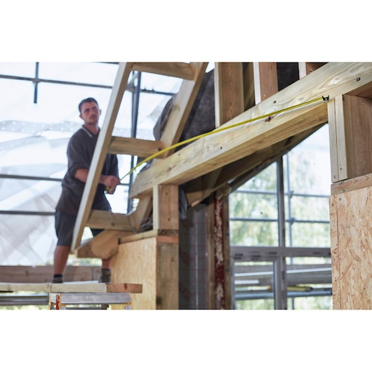 STANLEY FMHT0-36336 tape measure used for measuring wooden beams in construction.