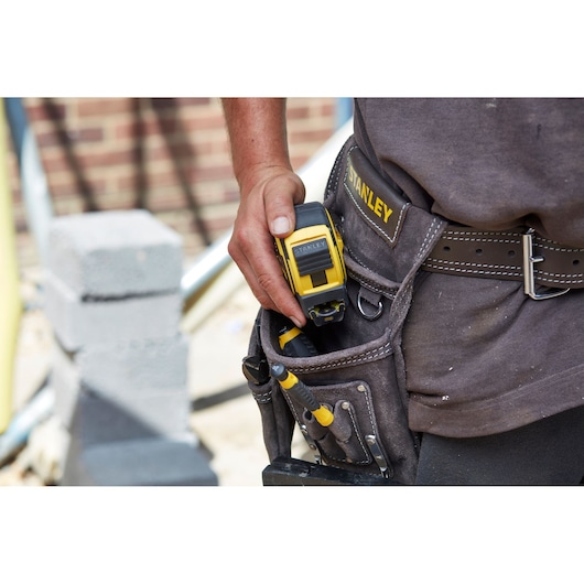 STANLEY FMHT0-36336 tape measure in tool belt pouch, photo on construction site.