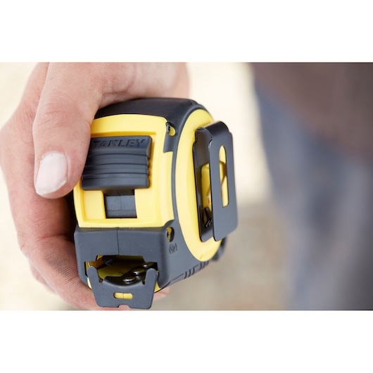 Photo of STANLEY FMHT0-36336 tape measure in hand, yellow and black, close-up side view.