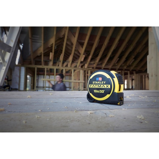 STANLEY FMHT0-36336 FATMAX 10m/33ft tape measure on construction site wooden floor.