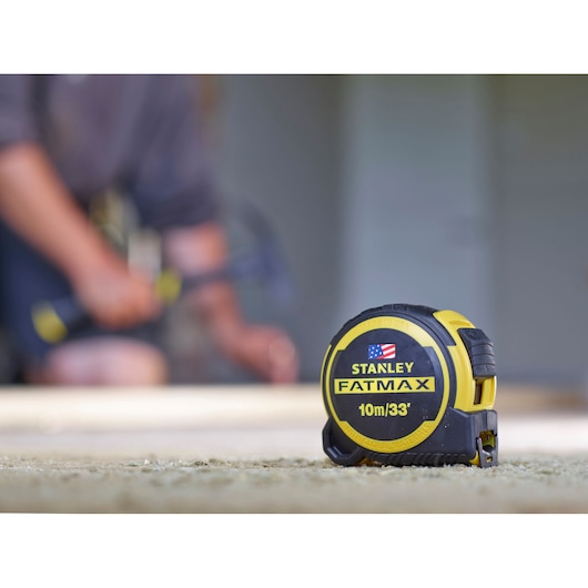 STANLEY FMHT0-36336 tape measure, yellow and black, FatMax 10m/33', shown on carpeted floor.