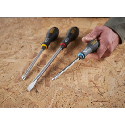 STANLEY FMHT0-62624 screwdriver set with color-coded handles, one held in hand on wooden surface, angled view.