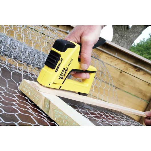 Photo of STANLEY FMHT0-70411 heavy-duty stapler in use on wire mesh and wood.