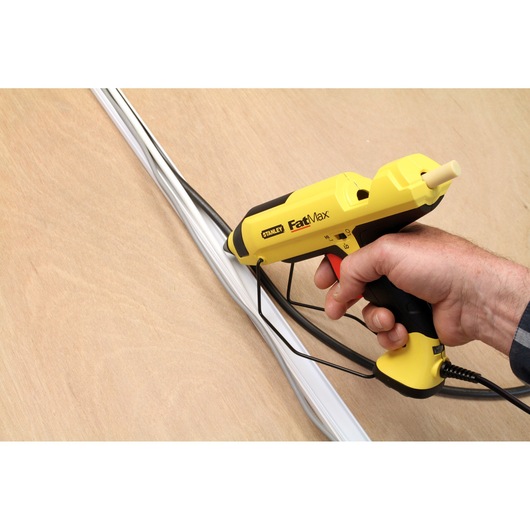 STANLEY FMHT0-70418 hot glue gun, yellow and black, hand-held, applying glue to white cables