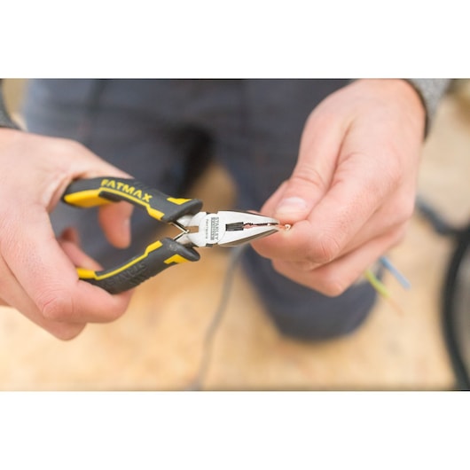 STANLEY FMHT0-80524 pliers with yellow and black handle gripping wire, close-up in hand.