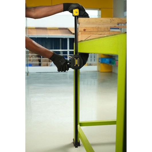 Stanley FMHT0-83241 bar clamp in use securing wood on a green workbench, close-up side angle.