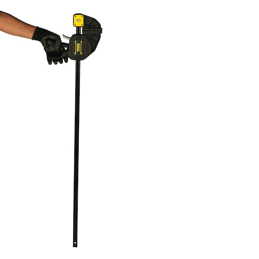 STANLEY FMHT0-83241 photography of black and yellow bar clamp held by a gloved hand, front angle.