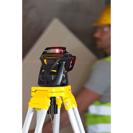 STANLEY FMHT1-77357 laser level on tripod with yellow base, shown in a worksite photography setting.