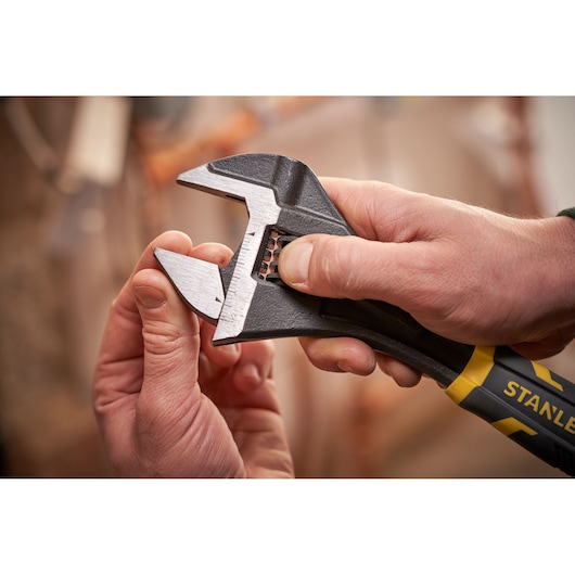 STANLEY FMHT13125-0 adjustable wrench with black and yellow handle held in hand, close-up view.