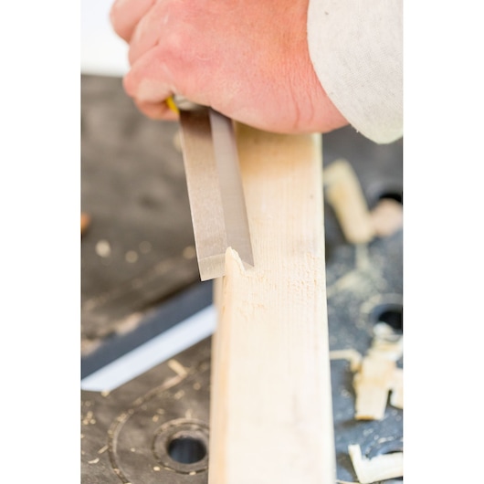 STANLEY FMHT16693-0 woodworking chisel in use, close-up view carving light wood.