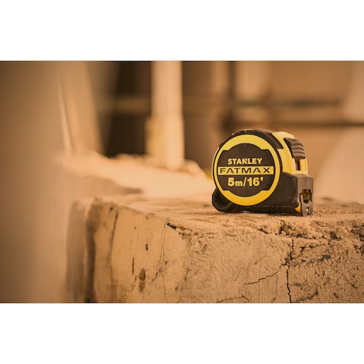 Photo of STANLEY FMHT33006-5 FATMAX tape measure 5m/16', black and yellow, on a rough concrete surface.