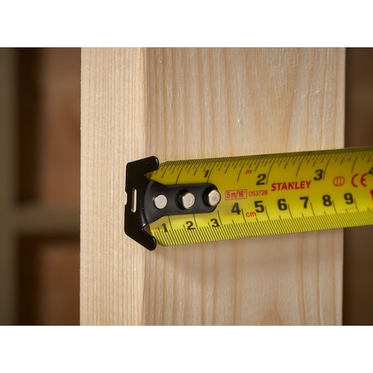 STANLEY FMHT33006-5 tape measure close-up measuring wooden plank, photography.