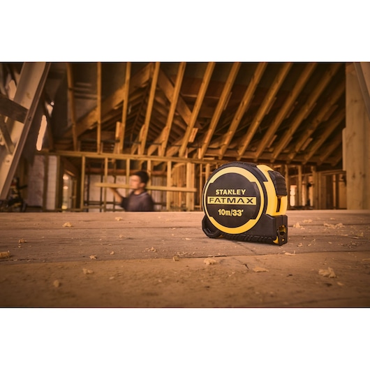 STANLEY FMHT33104-5 tape measure on wooden floor in construction site, yellow and black, 10m/33ft.