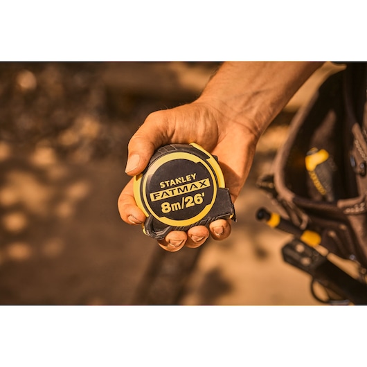 Photo of STANLEY FMHT33105-5 FATMAX 8m/26ft tape measure held in a hand, black and yellow casing.