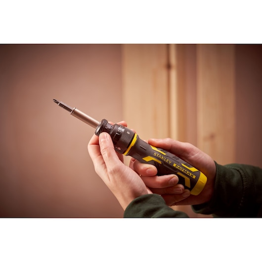 Photography of STANLEY FMHT62692-0 ratcheting screwdriver with yellow and black handle held in hand.