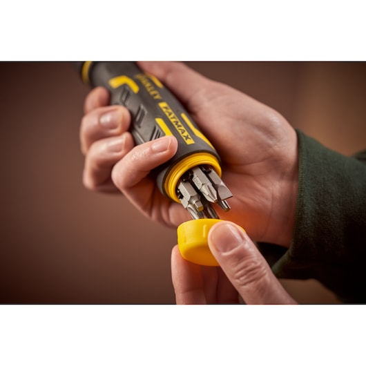 STANLEY FMHT62692-0 screwdriver with yellow cap open, showing multiple bits stored in handle, close-up view.