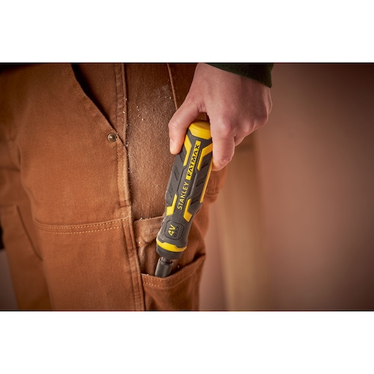 STANLEY FMHT66719-0 screwdriver with yellow and black handle, held beside a pocket on brown work pants.