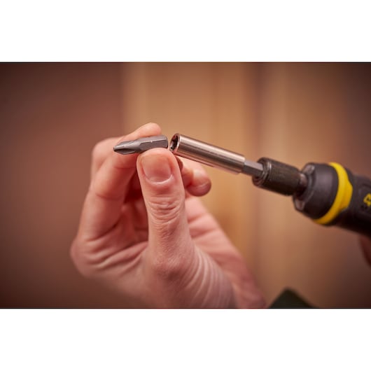 Stanley FMHT66719-0 screwdriver bit being inserted into a yellow and black tool, close-up photography.
