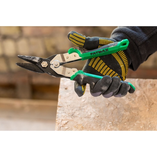 STANLEY FMHT73557-0 green handle aviation snips held in a gloved hand, close-up photo.