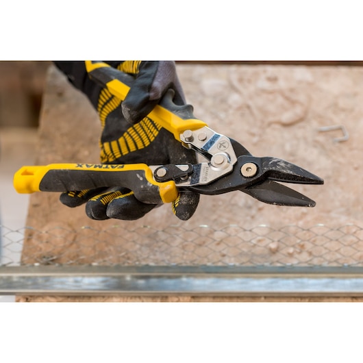 STANLEY FMHT73756-0 aviation snips with yellow and black handles held by gloved hand, cutting wire mesh.