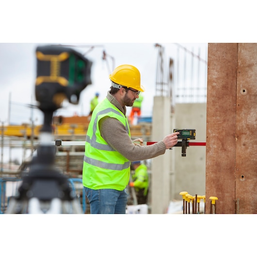 STANLEY FMHT77653-0 laser level in use at a construction site, worker in safety gear holding device.