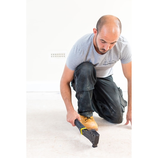 STANLEY FMHT81394-9 manual flooring stapler in use, person kneeling on unfinished floor.