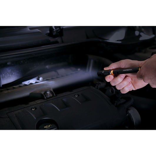 STANLEY FMHT81510-0 pen light flashlight used to inspect car engine in dark setting.