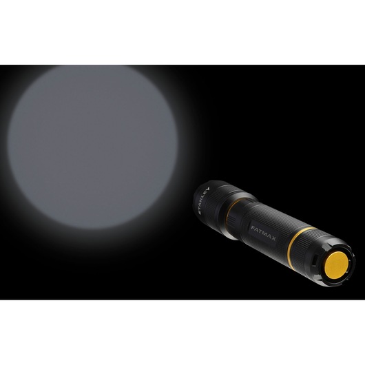 STANLEY FMHT81511-0 flashlight illuminating a wide beam, black and yellow design, angled on black background.