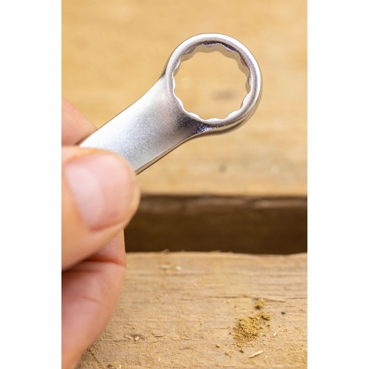 STANLEY FMMT13037-0 box-end wrench held in hand, close-up, silver finish, wooden surface background.