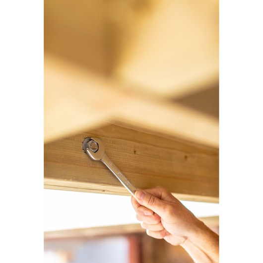 STANLEY FMMT82844-0 combination wrench used on a bolt in a wooden beam, close-up action shot.