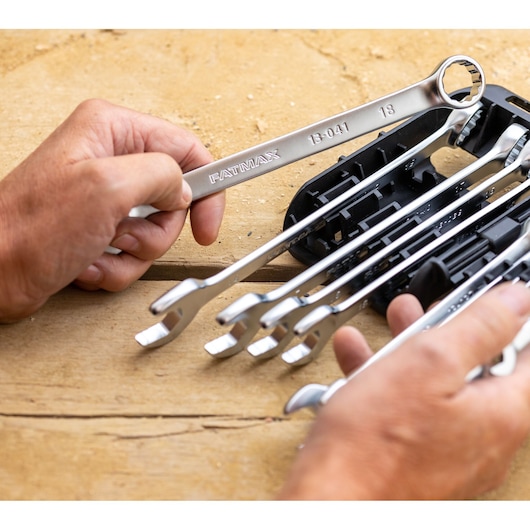 STANLEY FMMT82844-0 wrench set photography, hand holding silver wrenches on wooden surface.