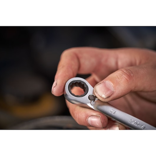 Close-up of hand holding STANLEY FATMAX FMMT82848-0 reversible ratcheting wrench, showing gear mechanism.