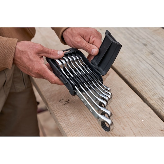 STANLEY FMMT82848-0 7-piece reversible ratcheting wrench set in case held by hands, photo on wooden surface.