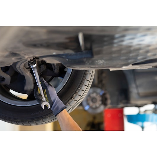 Photo of STANLEY FMMT82849-0 ratcheting wrench used on a car wheel by a gloved hand in a garage setting.