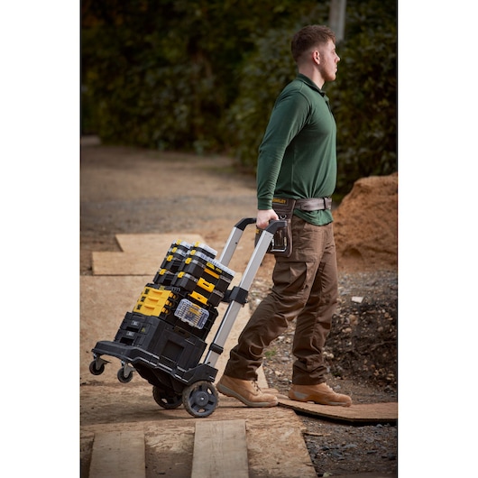 Stanley FMMT98103-1 mobile tool organizer stack on wheeled cart outdoors, carried by worker.