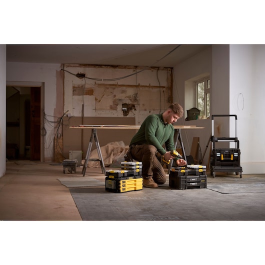 STANLEY FMMT98103-1 toolboxes and organizer in use on a construction site, worker kneeling beside them.